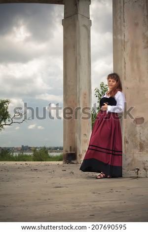 Beautiful romanian woman, dressed in popular costume, looking for cover in a rainy day