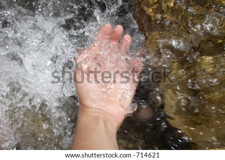Girl's hand in the water of a mountain river, Alps mountains, Italy