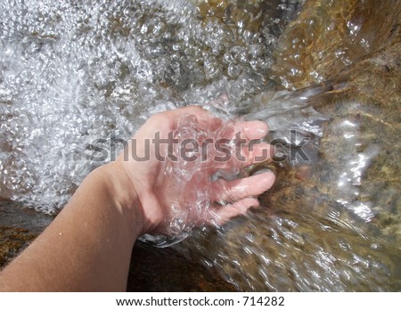 Girl\'s hand in the water of a mountain river, Alps Mountains, Italy
