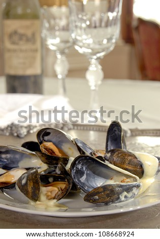 clams with sauce on a plate with bottle of wine