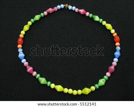 This is a glass bead necklace on a black material background. Multicolored hand-made jewelry.