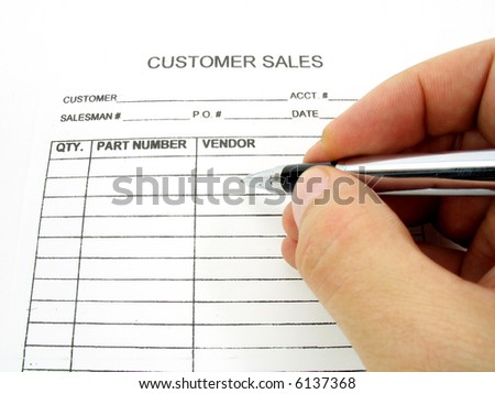 A hand with a pen about to write on a customer sales form. A blank invoice.