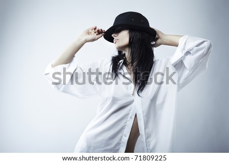 The seductive young beautiful brunette in a hat and a shirt