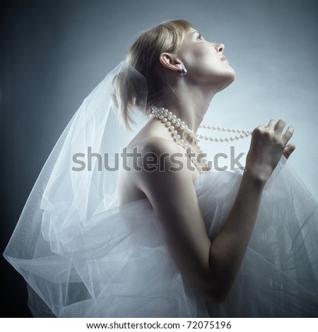 The fine young fair-haired woman in a pearl necklace and a white veil