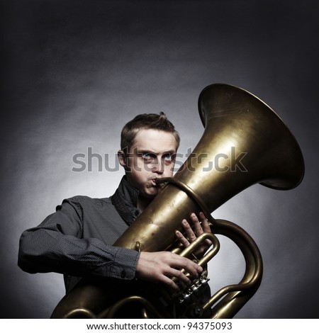 Portrait of a young man playing on the golden tuba