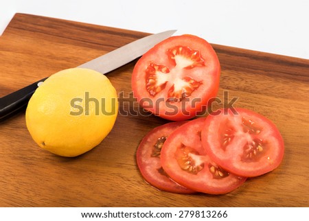 Lemon and sliced tomato on the wooden chopping block,white background