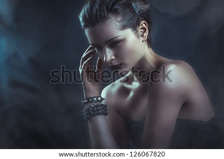 dramatic dark portrait of young attractive woman in clouds of smoke