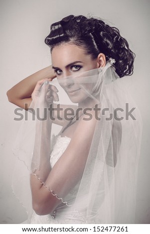 beautiful brunette bride holding veil over her smiling face