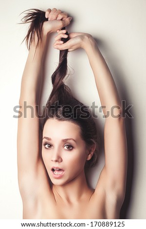 Pretty fun young beautiful girl pulls her long hair up hands