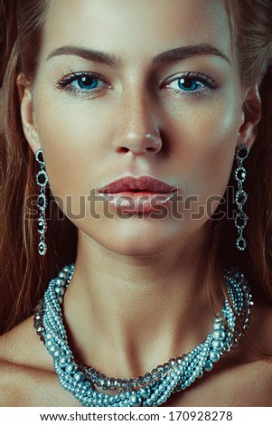 Close-up studio portrait of beautiful woman with bright make-up jewelry