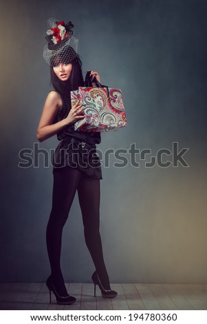 Beautiful girl in the studio with a bag in his hand and a hat on his head in full growth