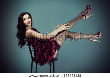 Pin up girl sitting on a bar stool lifting your legs up in stockings and dress corrects or dresses stockings