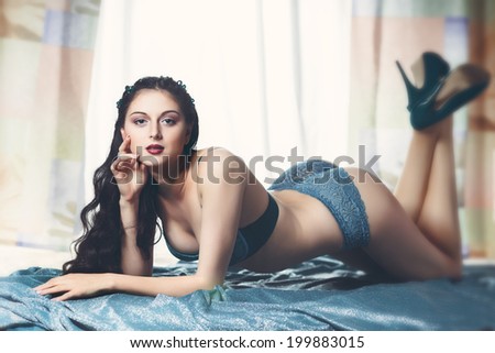 sexy brunette girl lying on the floor in stockings and blue lingerie and blue shoes