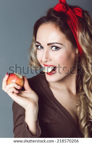 Portrait of beautiful young sexy blonde with a red armband with red lips with an apple, biting apple, healthy lifestyle, sensual temptation to make up pin up