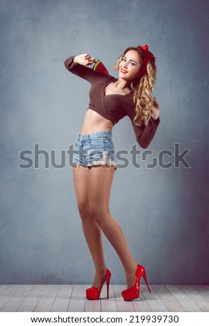 beautiful young sexy blonde slim figure with a red armband with red lips in denim shorts in red high heels with long legs of sensual temptation watermelon candy emotion surprise delight Pin Up