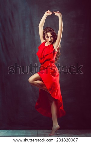 young beautiful and charming girl in red is dancing with a slender figure plastic body dancer with hair gymnast performs twine curly ringlet