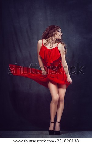 young beautiful and charming girl in red is dancing with a slender figure plastic body dancer with hair gymnast performs twine curly ringlet