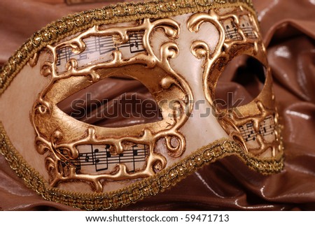 Ornate carnival venetian mask with music on gold silk background