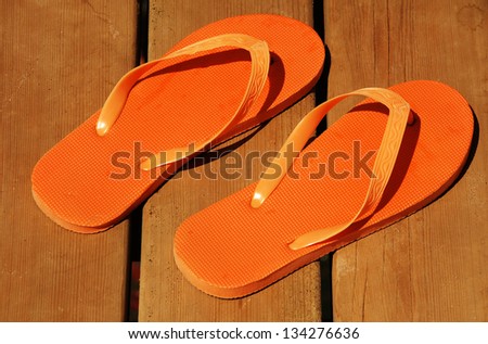 orange summer flip-flop sandals on wood deck background