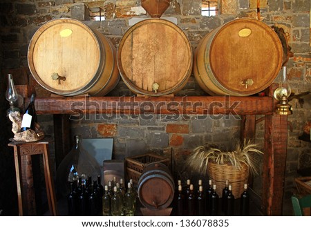 Wine barrels and bottles in the old cellar of a winery.