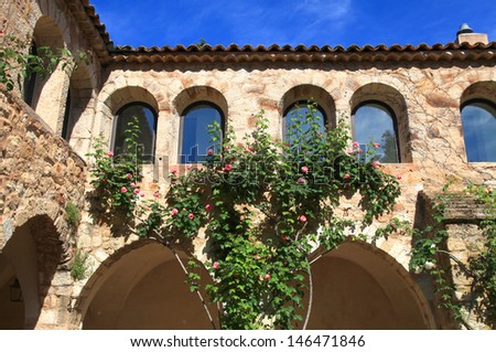 Beautiful medieval wall with arch windows in the patio with roses , Provence, France