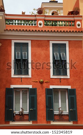 Beautiful red stucco house with old french green shutter windows and roof balcony in Monaco, Monte Carlo.
