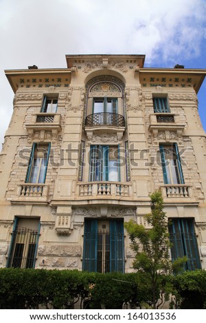 Beautiful Belle Epoque ornate stone building with balcony and traditional green shutter windows on blue sky background,Nice,Cote d\'Azur, France.