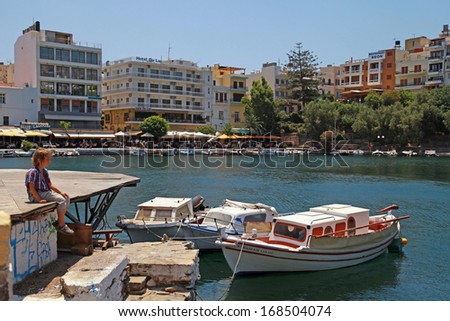 AGIOS NIKOLAOS, GREECE - JULY 18: Greek fishing boats, hotels and promenade cafe on July 18,2012 in harbor of Agios Nikolaos, Crete, Greece.