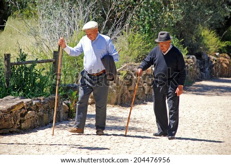 IDANHA-A-VELHA, PORTUGAL - MAY 04, 2009: Old men walks with a stick along stone path in medieval village Idanha-a-Velha, Portugal. Idanha-a-Velha - one of oldest towns in Portugal.