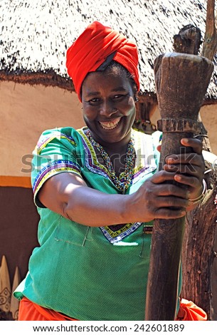 LESEDI,SOUTH AFRICA - JANUARY 1, 2008: Outdoor portrait of a beautiful black woman in Cultural village Lesedi, South Africa. She cooking traditional food and smiling .
