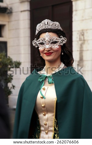 VENICE, ITALY - FEBRUARY 8, 2015: Beautiful unidentified masked woman in costume on San Marco Square during the Carnival in Venice, Italy.
