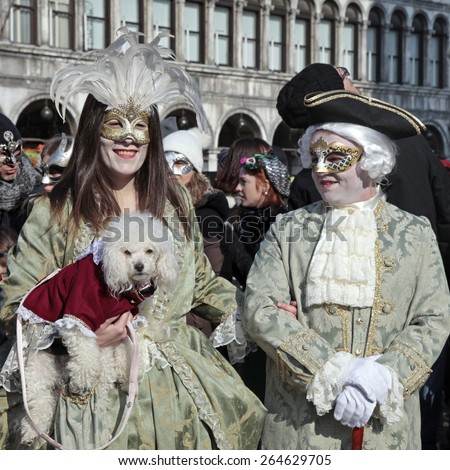 VENICE, ITALY - FEBRUARY 8, 2015: Two unidentified masked persons in costume with small dog on San Marco Square during the Carnival in Venice, Italy.