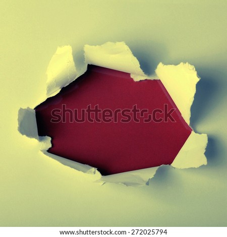 Round hole in paper with red background inside. Square toned image, instagram effect