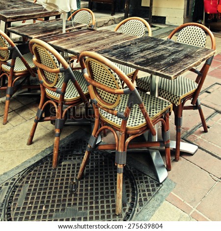 french outdoor cafe with wood tables and wicker chairs,Nice, Cote d\'Azur, France. Square vintage toned image