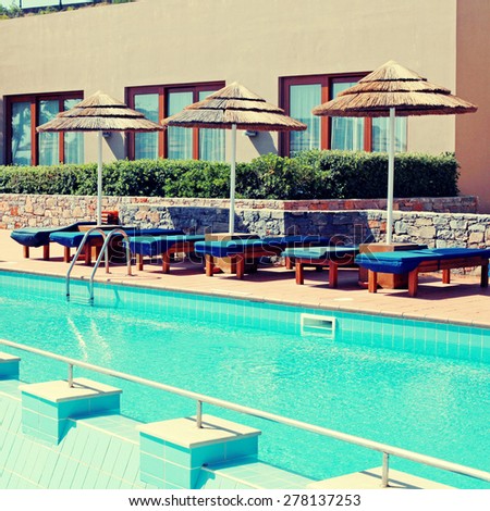 Summer landscape with pool, pool bed and umbrella in luxury resort hotel (Greece). Square toned image, instagram effect