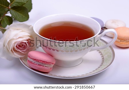 Cup of tea with pink french macaroon and pastel rose