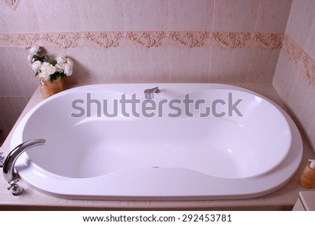 white bath tub with faucet and beige tiles in bathroom