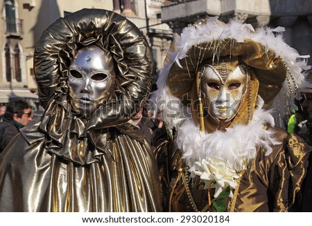 VENICE, ITALY - FEBRUARY 8, 2015: Two unidentified masked persons in golden costume on San Marco Square during the Carnival in Venice, Italy.
