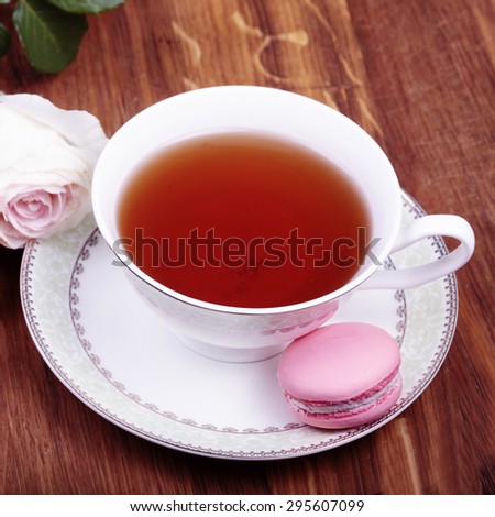 Cup of tea with colorful french macaron on wood background, square toned image, instagram effect