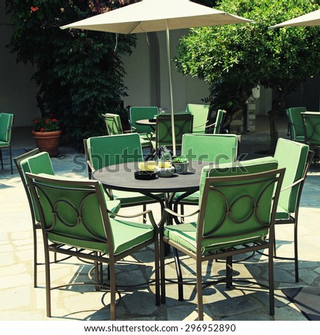 Iron tables and chairs with parasol in beautiful mediterranean patio cafe. square toned image, instagram effect