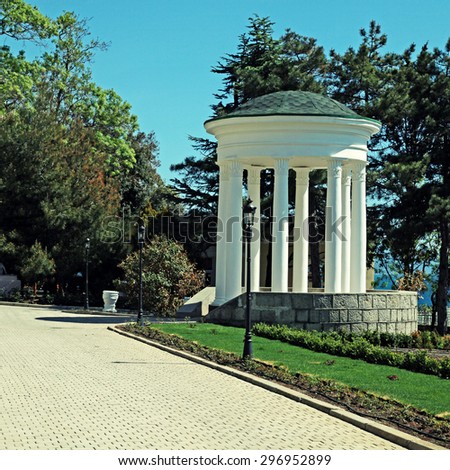 White classical rotunda and footpath in summer ornamental garden. Square toned image, instagram effect