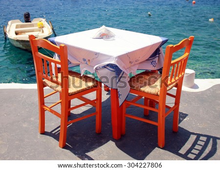 greek tavern with orange wooden chairs by the sea coast, Greece, Santorini island in Cyclades