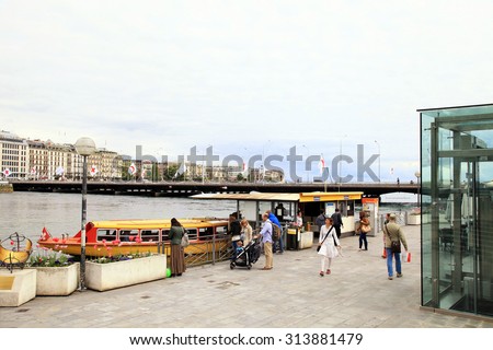 GENEVA, SWITZERLAND - MAY 11, 2013: Cityscape view with embankment and people on mouettes boats stop at the banks along Lake Geneva, Geneva, Switzerland.