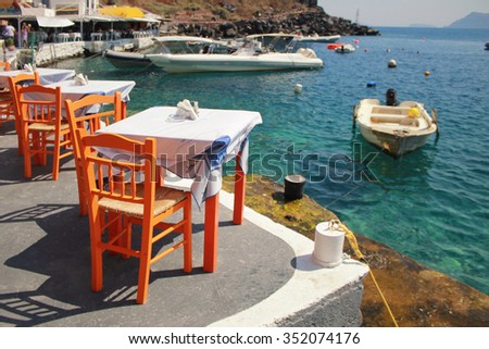 Greek tavern with orange wooden chairs by the sea coast, Greece, Santorini island in Cyclades. Selective focus