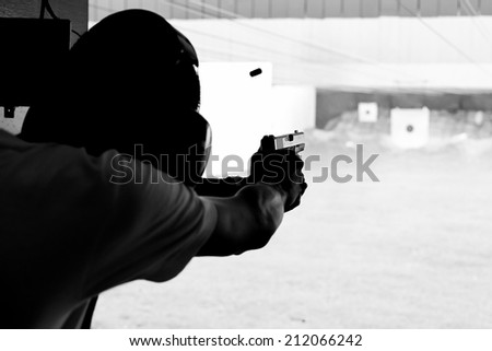 The man shooting gun silhouetted in black and white.