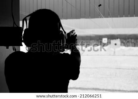 The man shooting gun silhouetted in black and white.