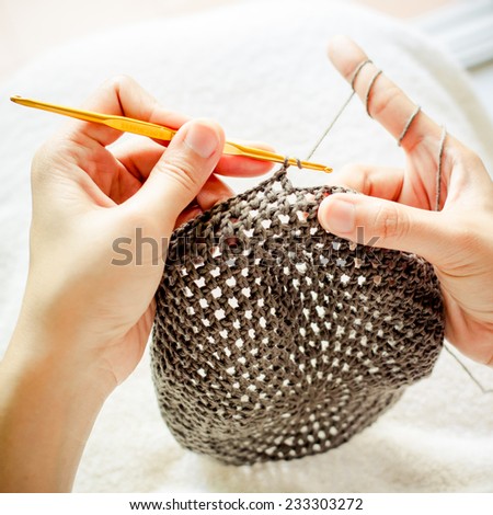 A women is doing a crochet hat in vintage colour tone.