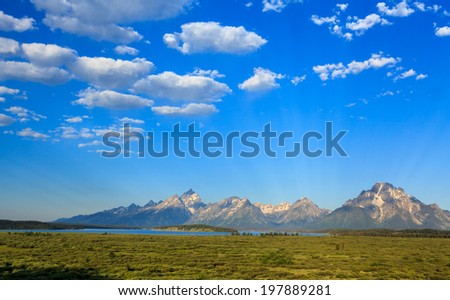 Jackson Lake in front of Teton Range in Grand Teton National Pak.  Taken in early morning, blue sky with spotty cloud
