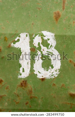 Number eighteen painted on a old green metal barrel