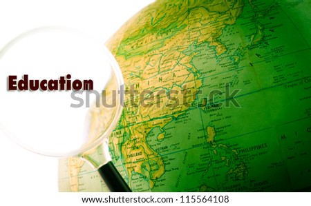 A green globe with a magnifying glass looking at the word education